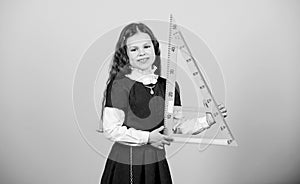Smart and clever concept. Girl with big ruler. School student study geometry. Sizing and measuring. Kid school uniform