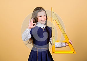 Smart and clever concept. Pupil cute girl with big ruler. School student study geometry. Sizing and measuring. Kid