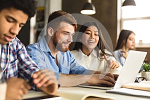 Smart college students networking on laptop in library