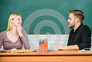 Smart and confident. Teacher and schoolmaster sitting at desk. Handsome man and pretty woman back to school. University