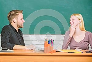 Smart and confident. Teacher and schoolmaster sitting at desk. Handsome man and pretty woman back to school. University