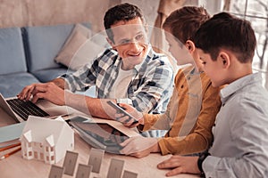 Smart devoted father telling his sons about renewable energy