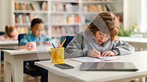 Smart diverse school kids writing in copybooks at desks