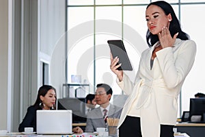 Smart and elegant business woman lady boss with black short hair in suit using digital tablet while confidential standing in the