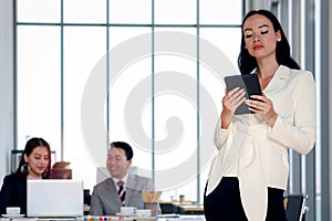 Smart and elegant fashionable business woman lady boss with black long hair using digital tablet while confidential standing in