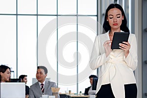 Smart and elegant fashionable business woman lady boss with black long hair using digital tablet while confidential standing in