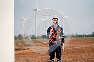 Smart engineer or technician man stand with holding light bulb and look at camera with background of windmill or wind turbine and