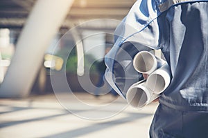 Smart Engineer wear bear suit holding building plan on hand at the construction site. Construction Concept