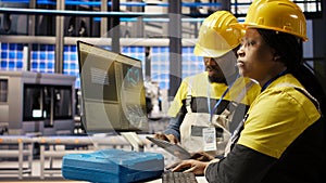 Smart factory manager overseeing work done by engineer calibrating machinery