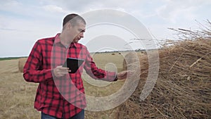 Smart farming agriculture concept. man farmer studying a haystack in a field on lifestyle digital tablet. slow motion
