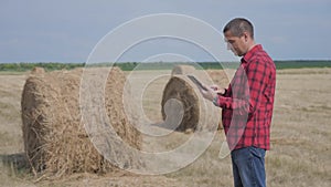 Smart farming agriculture concept. man farmer worker studying a haystack in a lifestyle field on digital tablet. slow