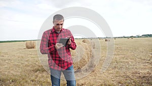 Smart farming agriculture concept. man lifestyle farmer studying a haystack in a field on digital tablet. slow motion