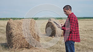 Smart farming agriculture concept. man worker farmer studying a haystack in lifestyle a field on digital tablet. slow