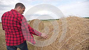 Smart farming agriculture lifestyle concept. man farmer studying a haystack in a field on a digital tablet. slow motion