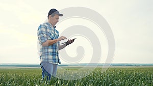 Smart farming. Man agronomist a farmer red neck with digital tablet computer in green wheat field using apps and