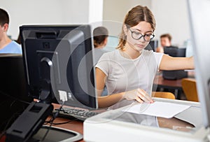 Smart female teenager learning computer science while she is using a PC and scanner in the computer classroom