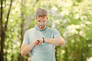 Smart fitness. Fit athlete tracking his fitness activity with sports watch. Handsome athlete using fitness tracker