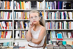 Smart girl child bemused a lot of books in a bookstore