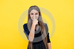 Smart girl child with long hair and eyeglasses on yellow background, nerd