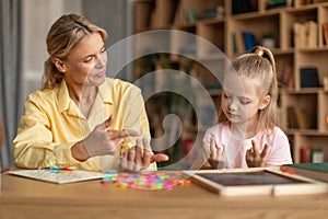 Smart girl counting on fingers, studying with private teacher in office and learning the numbers, sitting at desk