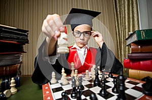 Smart girl in graduation cap making move at chess with horse