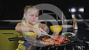 Smart girl learning to cook. Young mistress children to cook a Neapolitan egg fried omelette from salame affumicato