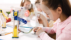 Smart girl programming robot, working with wires and circuits