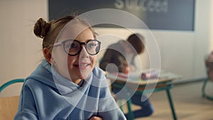 Smart girl raising hand at lesson. Smiling student answering question