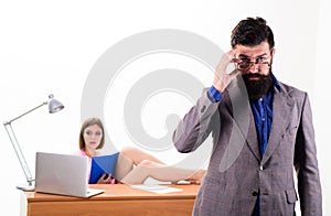 Smart and good looking guy. Smart man looking through glasses with sexy woman working in background. Bearded man in