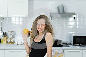 smart healthy woman happy, smile, hold orange in hand before mixing healthy fruit juice in kitchen with copy space. beautiful