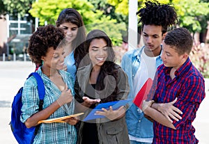 Smart hispanic female student learning with group of latin and african american young adults