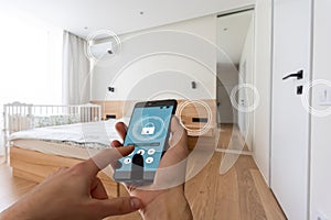 Smart home automation app on smartphone hold by female hand with home interior in background