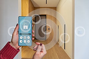 Smart home automation app on smartphone hold by female hand with home interior in background