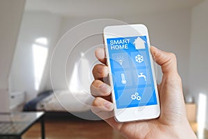 Smart home automation app on smartphone hold by femaleâ€™s hand with home interior in background