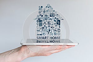 Smart home automation concept. Background with hand holding smart phone and floating text and icons.