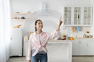 Smart Home Concept. Smiling Woman Pointing Finger Up In Air