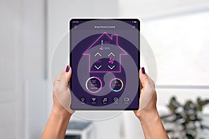Smart home control app on tablet in woman hands. Home interior in background