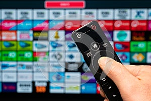 Smart home, hand with remote control, on the background apps on the smart television