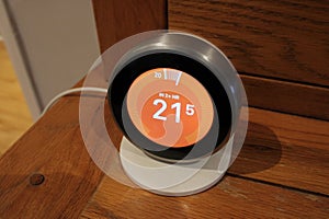 Smart home thermostat sitting on a wooden decor indoors