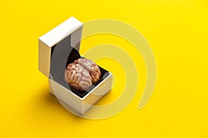 Smart human brain in box is isolated on yellow background as gift to dumb person. Mental development, self-improvement or problems