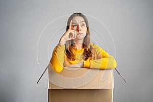 Smart idea concept. Teenager student girl sitting inside box looking up thinking of idea, solution or plan.