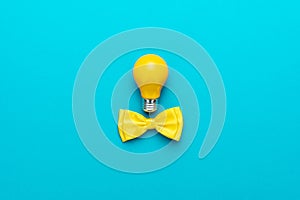 Smart idea with yellow bulb, bow tie on turquoise blue background and copy space