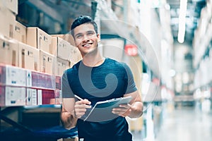 Smart Indian engineer man worker doing stocktaking of product management in cardboard box on shelves in warehouse.