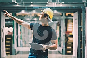 Smart Indian engineer man worker wearing safety helmet doing stocktaking of product management