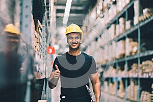 Smart Indian engineer man worker wearing safety helmet doing stocktaking of product management in cardboard box on shelves