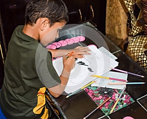 Smart Indian little boy drawing with colourful pencils kit of various colours during the summer vacations, Cute Indian Kid