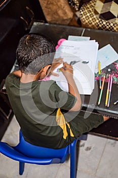 Smart Indian little boy drawing with colourful pencils kit of various colours during the summer vacations, Cute Indian Kid