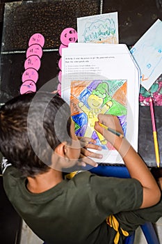 Smart Indian little boy drawing with colourful pencils kit of various colours during the summer vacations, Cute Indian Kid