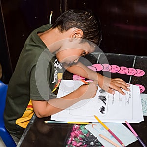 Smart Indian little boy drawing with colourful pencils kit of various colours during the summer vacations, Cute Indian Kid