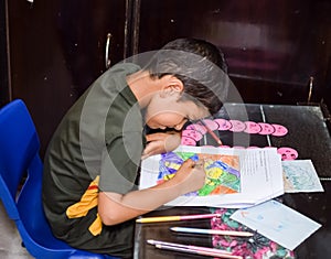 Smart Indian little boy drawing with colourful pencils kit of various colours during the summer vacations, Cute Indian Kid